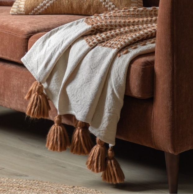 Rust and cream woven throw with tassels draped over a sofa
